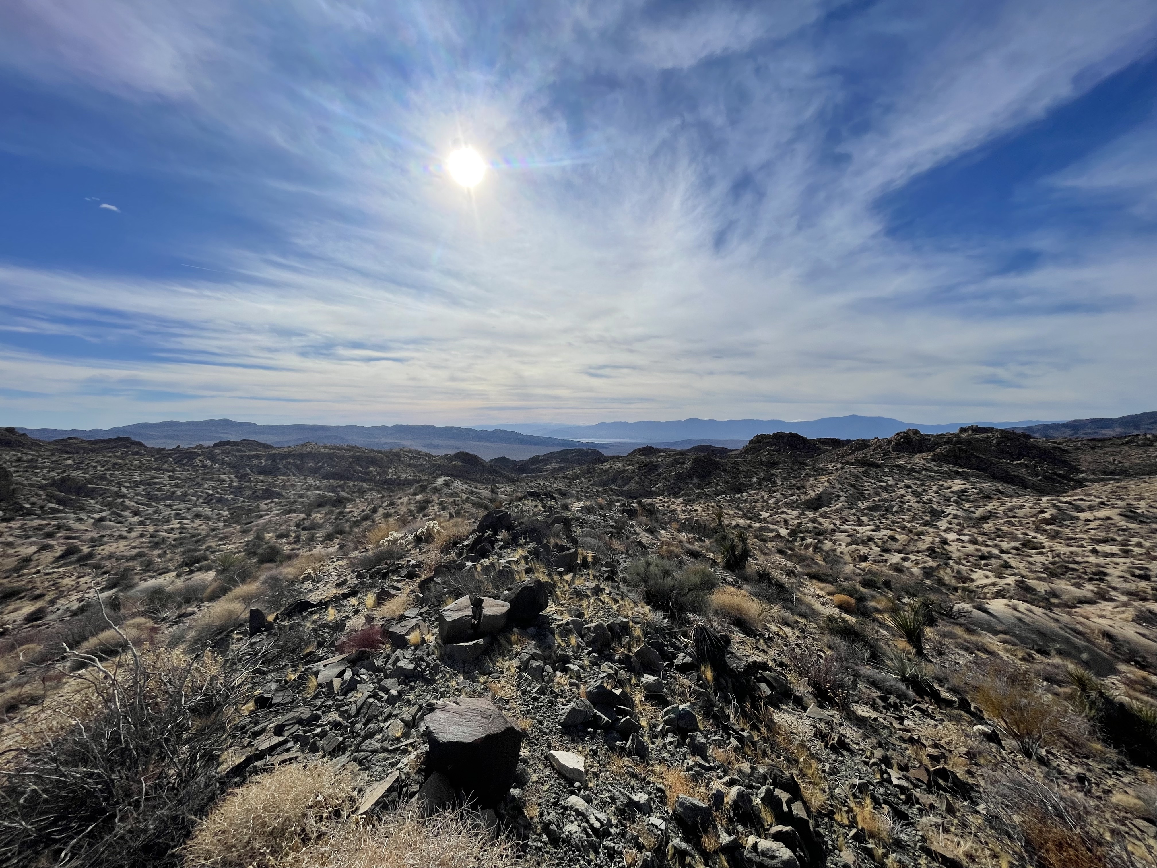 Desert with blue sky, sun, and some clouds