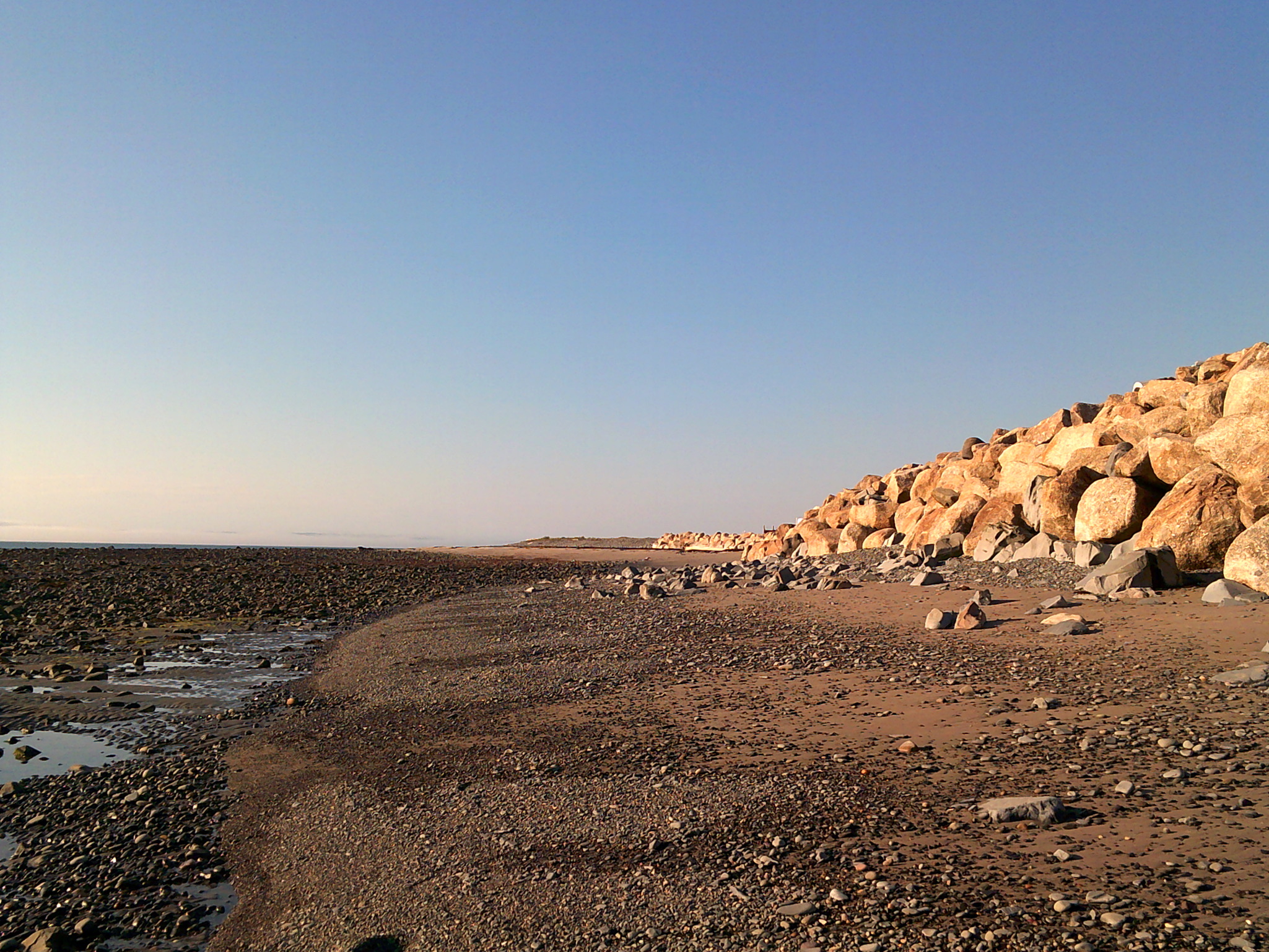 Pebbles on a beach with rocks to the side